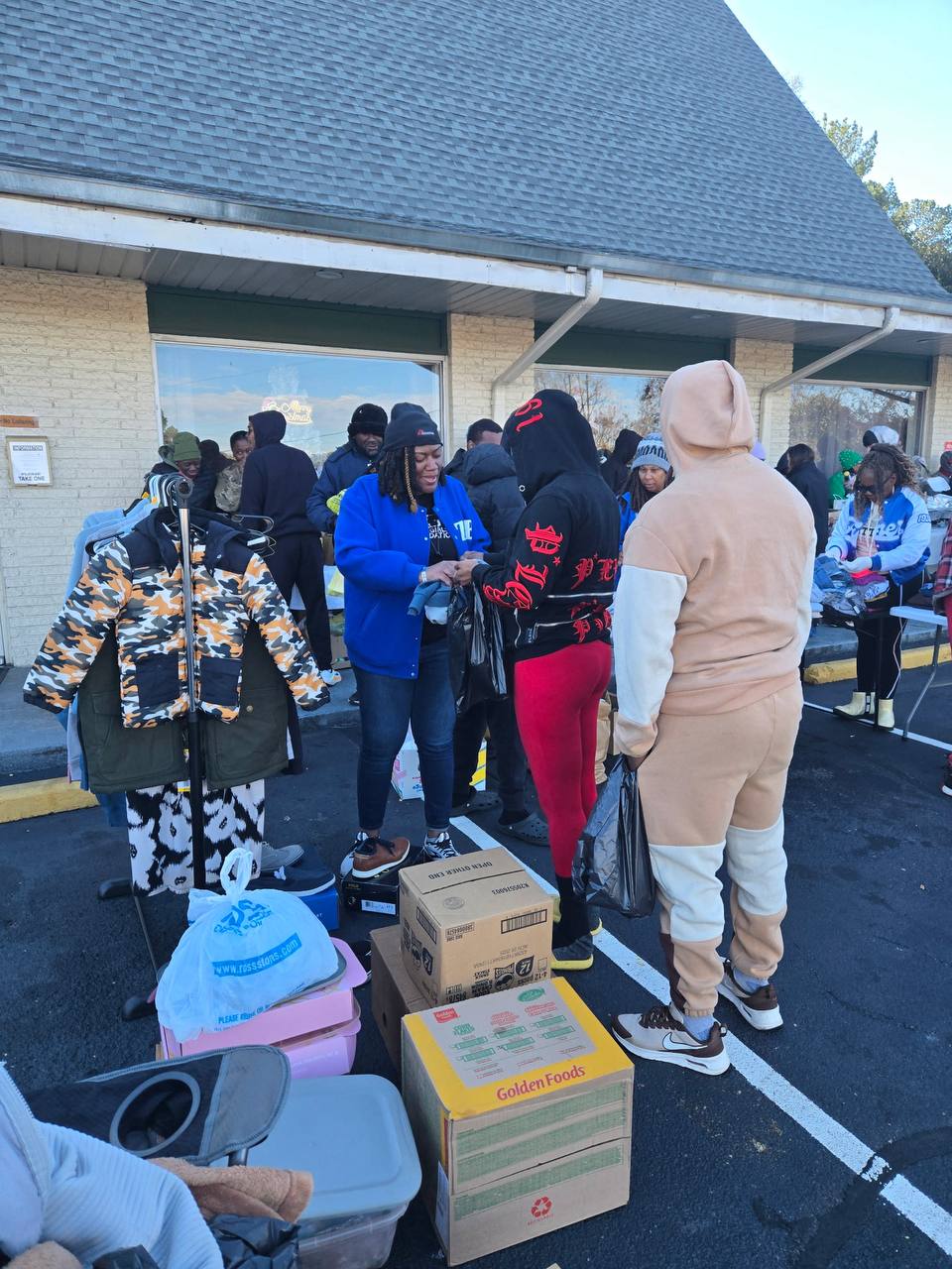 Volunteers helping community members select coats and clothing at an outdoor distribution