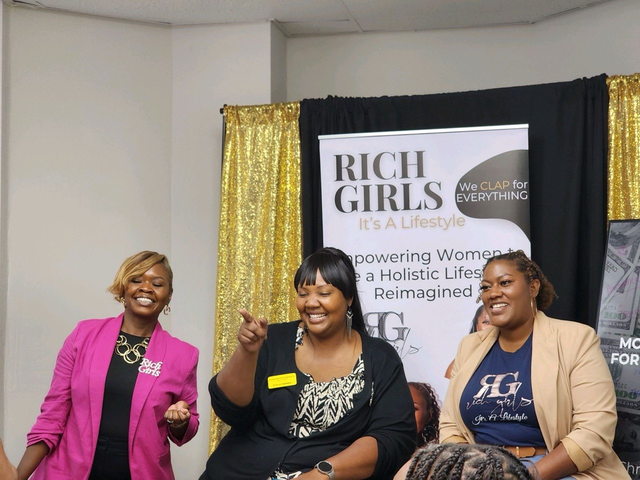 Rich Girls representatives speaking and laughing during a workshop in front of the Rich Girls banner